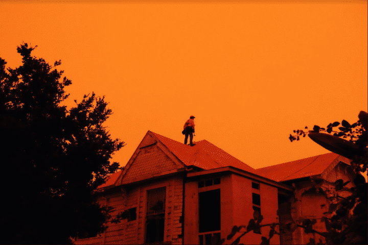 a man standing on the roof of a house in orange light